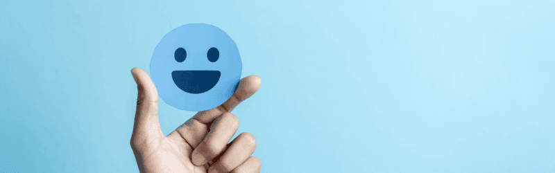 Blue Smiley Face Paper Cutout Being Held By Hand